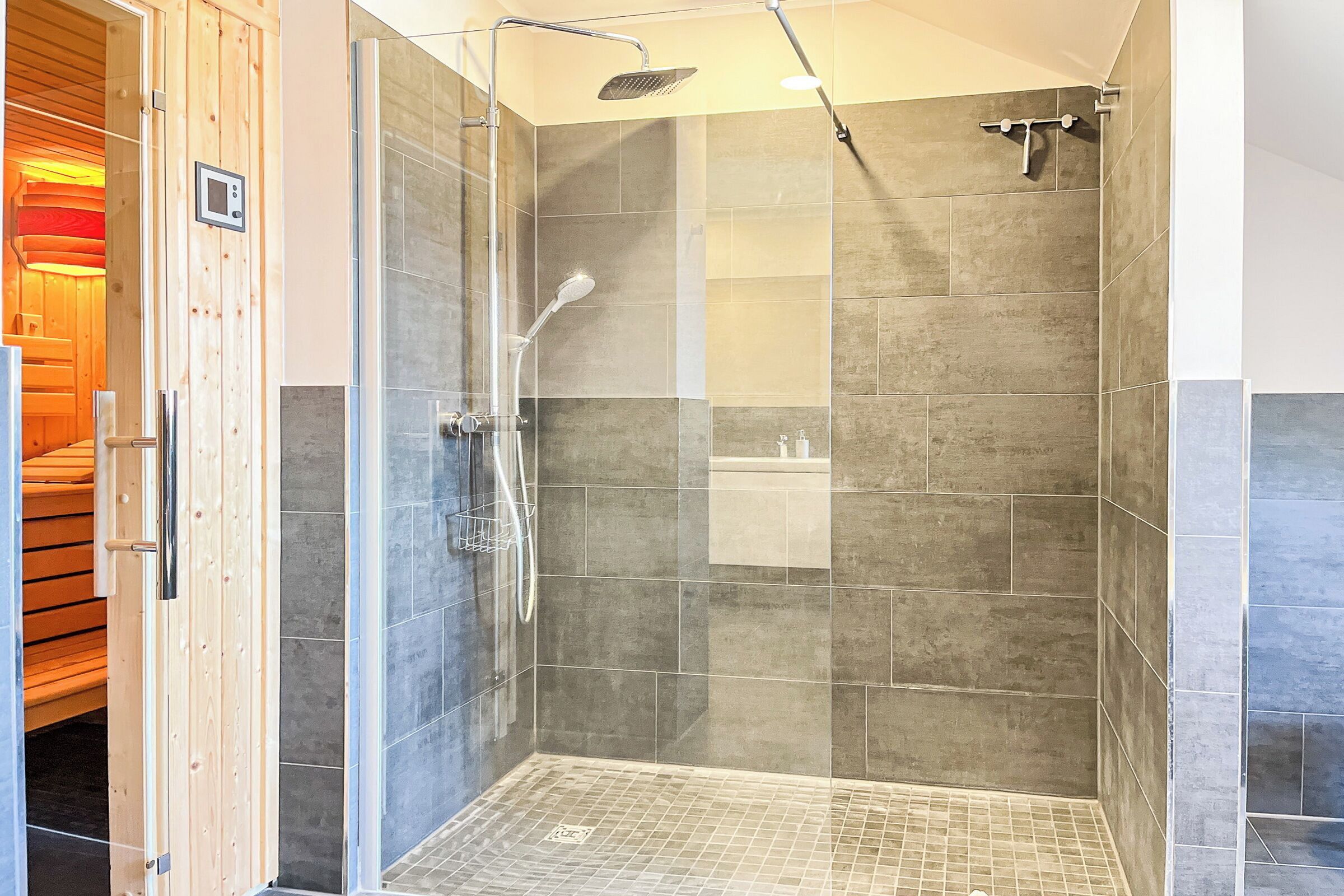 Una ducha moderna con puerta de vidrio, paredes con azulejos y un banco de madera en el exterior.