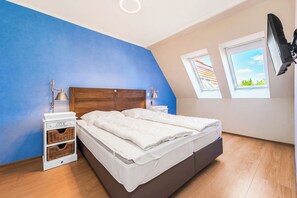Ein Schlafzimmer mit einem Bett, Nachttischen, einer Lampe, einem Fernseher und einem Fenster.