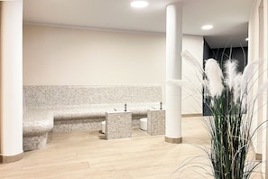 Ein modernes Badezimmer mit Sitzbank, zwei Waschbecken und einer Zierpflanze.