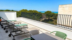 A balcony with outdoor furniture, a view of the sea, and a railing.