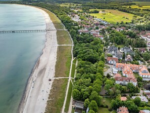 Luchtbeeld van een kustplaats met een strand, woongebouwen en een brug.