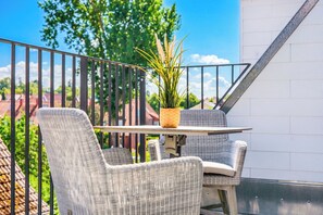 A balcony with wicker furniture, a potted plant, and a view of the neighborhood. - Baltischer Hof apartment 47 (Osteebad Boltenhagen)