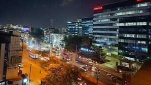 A nighttime cityscape with a prominent building labeled "ORACLE" and a busy street with vehicles. - Astra Hotel and Suites Kaadubesanahalli (Kadubeesanahalli)