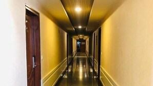 A long, narrow hallway with a polished floor, wooden doors, and a ceiling with recessed lighting. - Astra Hotel and Suites Kaadubesanahalli (Kadubeesanahalli)