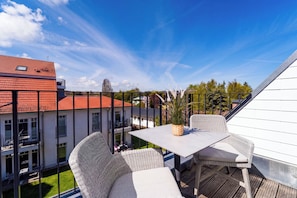 A balcony with wicker furniture, a table, and a potted plant. - Baltischer Hof 57 Apartment (Ostseebad Boltenhagen)