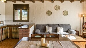 Une cuisine avec un mur recouvert de briques, des poutres en bois au plafond et un coin repas comprenant une table et des chaises.