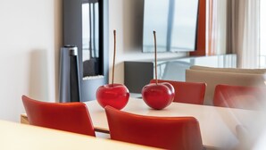 Un comedor moderno con una mesa blanca, sillas rojas y dos manzanas rojas sobre la mesa.