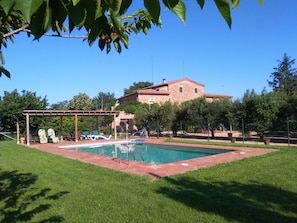 A pool area with a pergola and lounge chairs, surrounded by a well-maintained lawn and a stone building in the background. - La Parra at Mas Pareta: Rural Retreat Surrounded by Nature (Fonolleres (Parlavà))