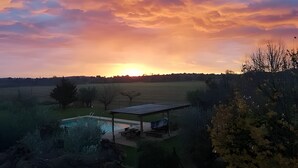Un capvespre sobre un paisatge rural amb piscina i un pavelló cobert.