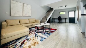 Una sala de estar moderna con un sofá, una mesa de centro y una escalera que lleva a un nivel superior.