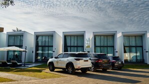 Un edificio moderno con ventanas amplias y un estacionamiento con varios SUVs.