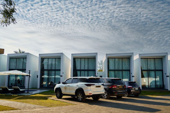 A modern building with large windows and a parking area with several SUVs.