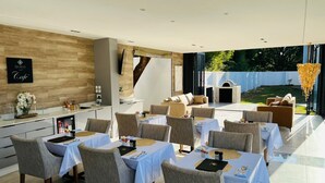 Un comedor moderno con mesas dispuestas para comensales, una zona de cocina y vistas al exterior.