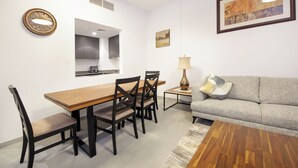 Un salon moderne comprenant un canapé, une table basse en bois, une table à manger avec des chaises, une horloge murale et un tableau.