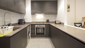 Une cuisine moderne avec des meubles de couleur sombre, une hotte en acier inoxydable, un four encastré et une machine à caf é.