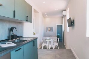 A modern kitchen with a built-in stove, a sink, and a dining area with a table and chairs. - Apartment with panoramic terrace in historic center (Napoli)