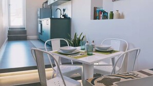 A compact kitchen with a dining area, featuring white chairs, a small table, and a view of the adjacent living space. - Apartment with panoramic terrace in historic center (Napoli)