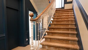 Eine Treppe mit einem Holzgeländer und weißen Spindeln, die zu einem dunklen Raum führt.
