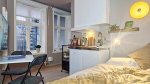 A compact bedroom with a bed, bedside table, and a small desk area. - Cozy, Central Studio by the Bus Station (Bergen)