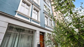 A building with large windows and a door, surrounded by greenery. - Cozy, Central Studio by the Bus Station (Bergen)