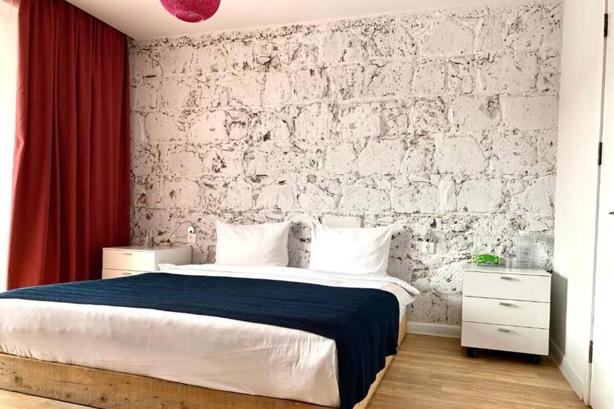 A bedroom with a bed, a nightstand, a dresser, and a textured wall.