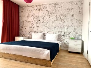 A bedroom with a bed, a nightstand, a dresser, and a textured wall. - Vardeni Guest House (Hrazdan)
