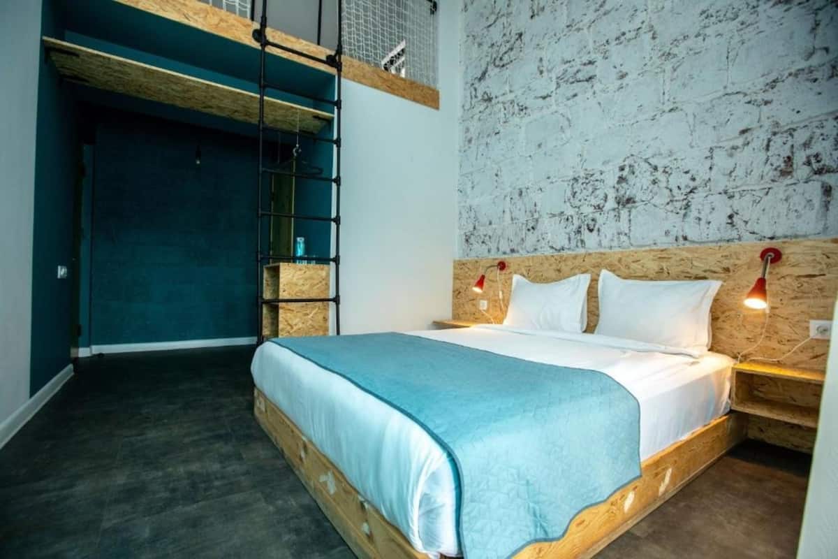 A bedroom with a bunk bed, a wooden headboard, a light blue bedspread, and a wall with a distressed texture.