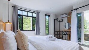 Ein Hotelzimmer mit einem großen Bett, einem Schreibtisch, einem Stuhl und einem Balkon mit Blick auf Grünflächen.