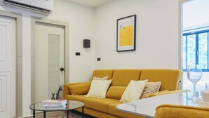 Ein Wohnzimmer mit einem gelben Sofa, einem kleinen runden Tisch und einem gerahmten Bild an der Wand.