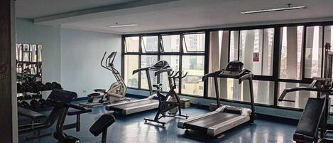 A gym with treadmills, elliptical machines, and weight benches.