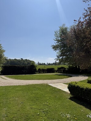 Ein gepflegter Garten mit Kiesweg, ordentlich geschnittenen Hecken und verschiedenen Bäumen.