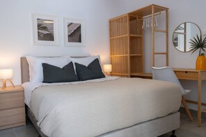 A bedroom with a bed, bedside tables, a desk, a chair, a wardrobe, and wall-mounted artwork. - Sienna Townhouse by Staycom (Paphos)