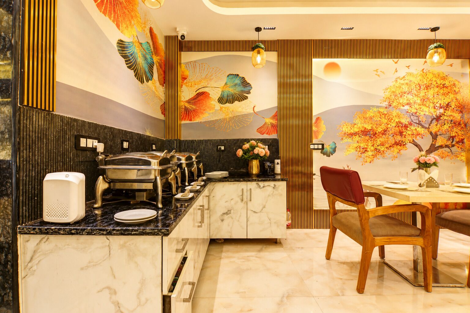 A modern kitchen with a marble countertop, a buffet setup, and a dining area with a table and chairs.