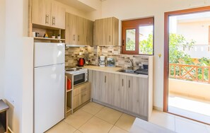 A compact kitchen with a refrigerator, microwave, stove, and coffee maker. - Aloustina Apartment for 4, 50m from the Sea in Archangelos (Archangelos)