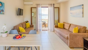 Ein Wohnzimmer mit einer Couch, einem Esstisch mit Früchten und einem Balkon mit Blick.