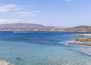 A coastal landscape with clear blue waters, rocky shorelines, and distant mountains. - Aloustina Apartment 50m from the Sea in Archangelos (Archangelos)
