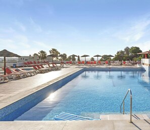 A swimming pool with lounge chairs and umbrellas, surrounded by a clear sky and palm trees. - Jardim Cozy Apartment With Pools Near the Old Town (Albufeira)