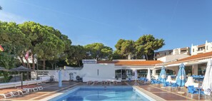 A pool area with lounge chairs and umbrellas, a restaurant sign, and a building with a tiled roof. - Jardim Cozy Apartment With Pools Near the Old Town (Albufeira)