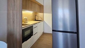 Eine moderne Küche mit Holzausstattung, einem Edelstahlkühlschrank und einem eingebauten Backofen.