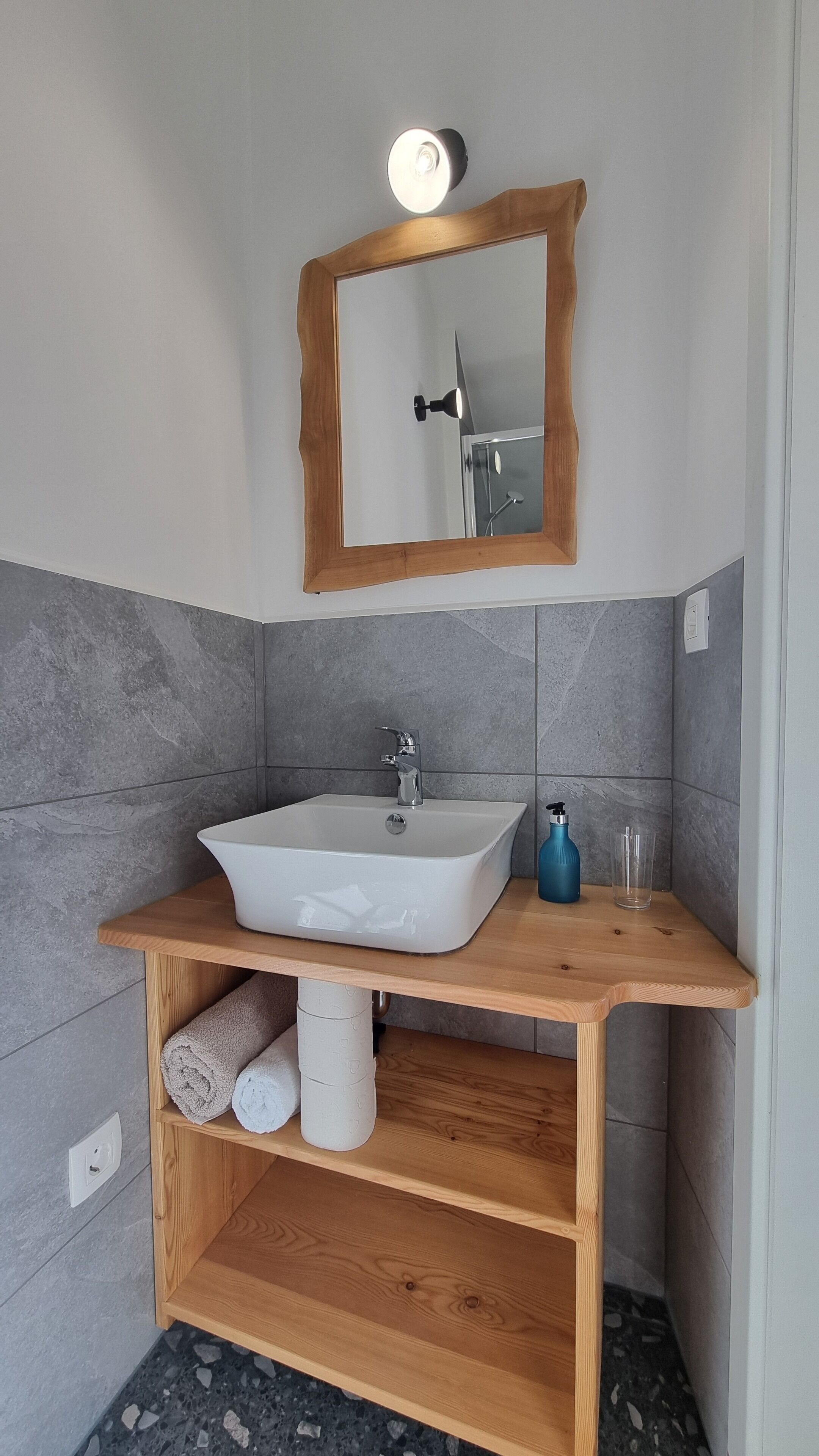 A bathroom with a white sink, a wooden vanity, a mirror with a wooden frame, and a towel rack.