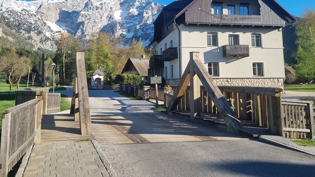 Hotel med udsigt til et bjerg, en træterrasse, stenvægge og bjergpanorama.