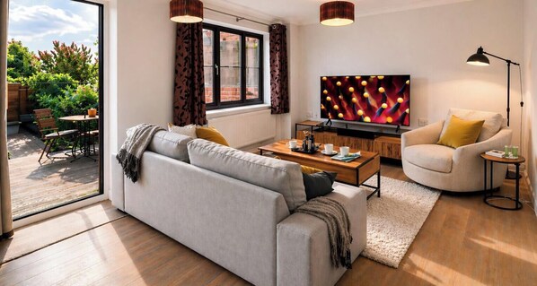 Uma sala de estar moderna com sofá, mesa de centro, televisão e área de jantar com cadeiras e mesa.