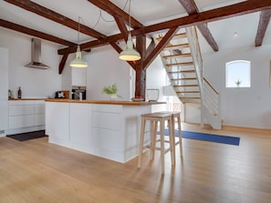 A modern kitchen with white cabinets, a wooden island, and pendant lighting. - 4 Star Holiday Home in Lokken (Lokken)