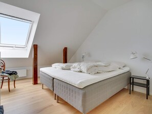 A bedroom with a bed, a desk, a chair, a radiator, and a skylight. - 4 Star Holiday Home in Lokken (Lokken)