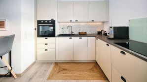Een moderne keuken met witte kasten, een inbouwoven, een spoelbak en een magnetron.