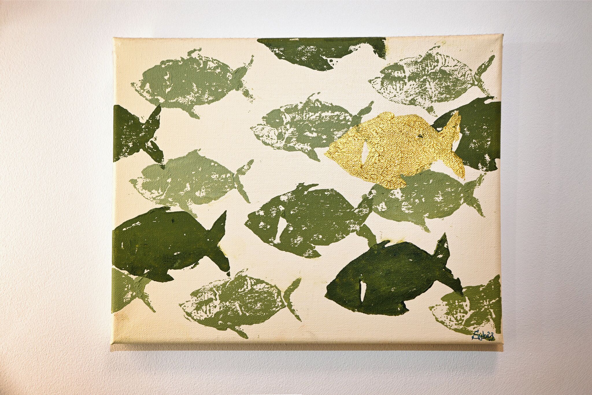 Ein quadratisches Gemälde mit einem Muster aus Fischsilhouetten in verschiedenen Grüntönen auf beigem Grund.