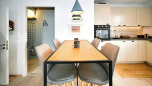 Een moderne keuken met witte kasten, een houten eettafel en een hangende lamp.