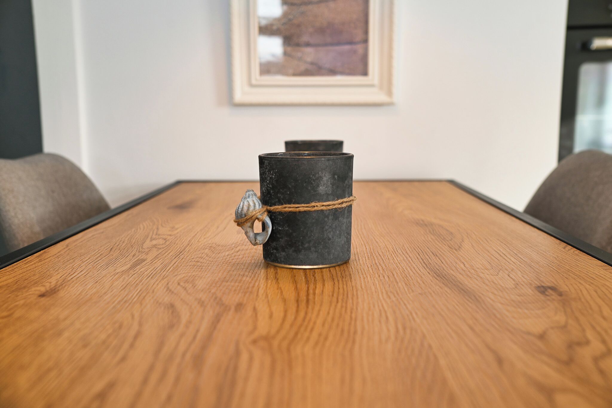 A wooden table with a black cylindrical object tied with a rope.