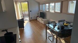 Una cocina moderna con comedor, televisor y vistas a la ciudad a través de amplios ventanales.