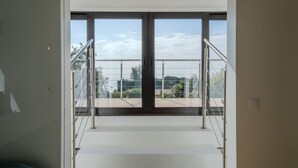 A modern interior with a staircase leading to a balcony with glass doors and metal railings. - Villa d’exception, Vue mer et Rooftop Super Cannes (Vallauris)